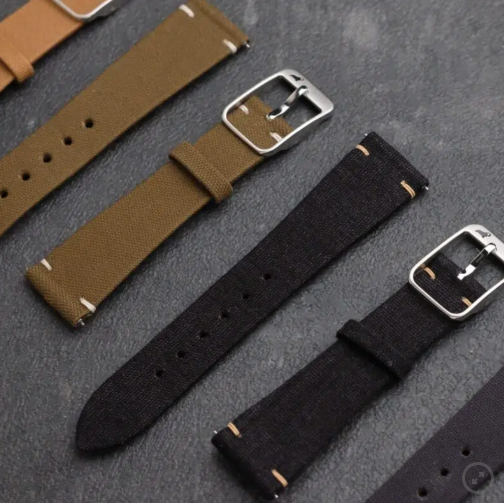 The RSM Fine Canvas watch strap showcases a sleek design with a silver buckle, quick-release spring bars, and adjustable holes, resting on a dark surface.