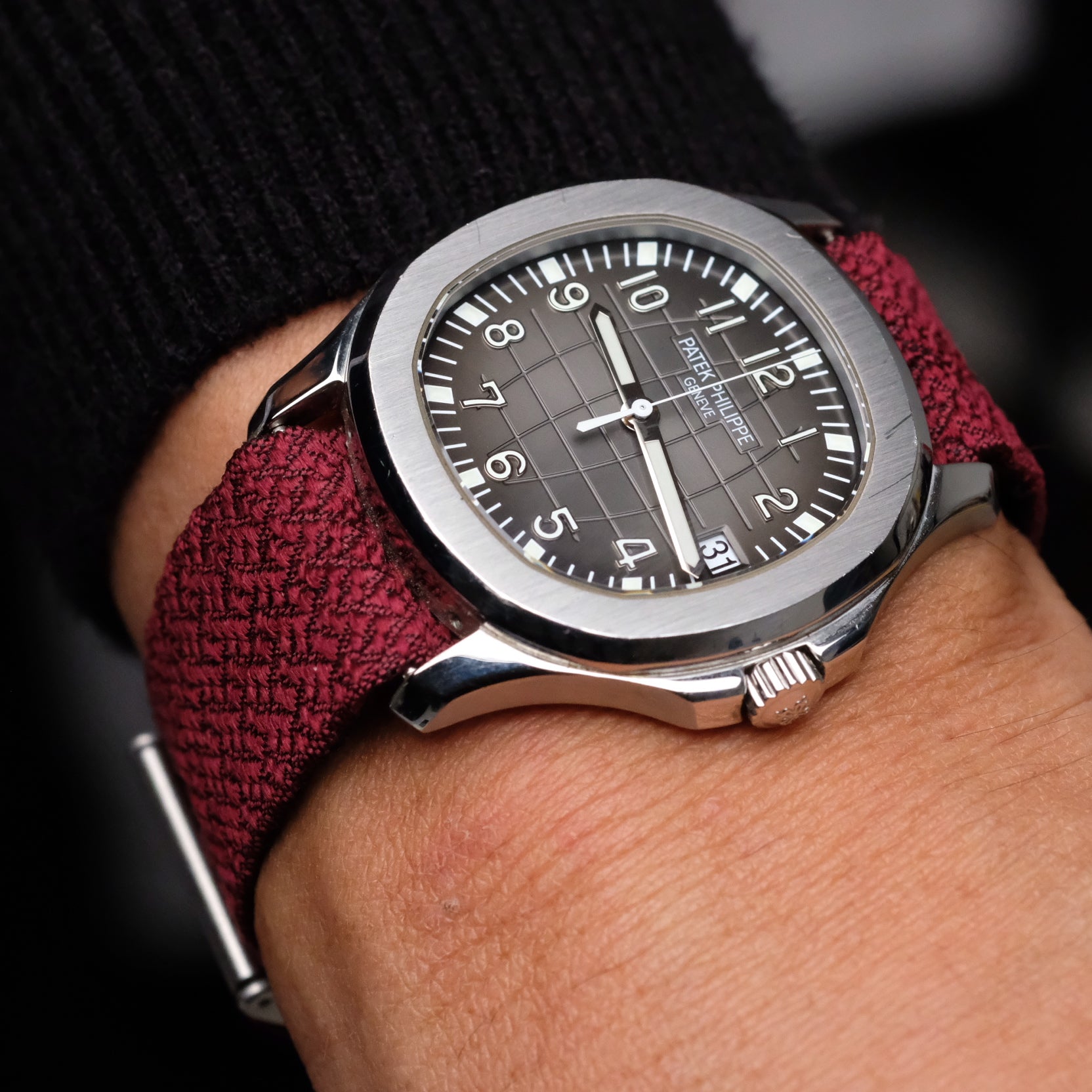 A Patek Philippe Watch with a burgundy reversible silk watch strap on a wrist.