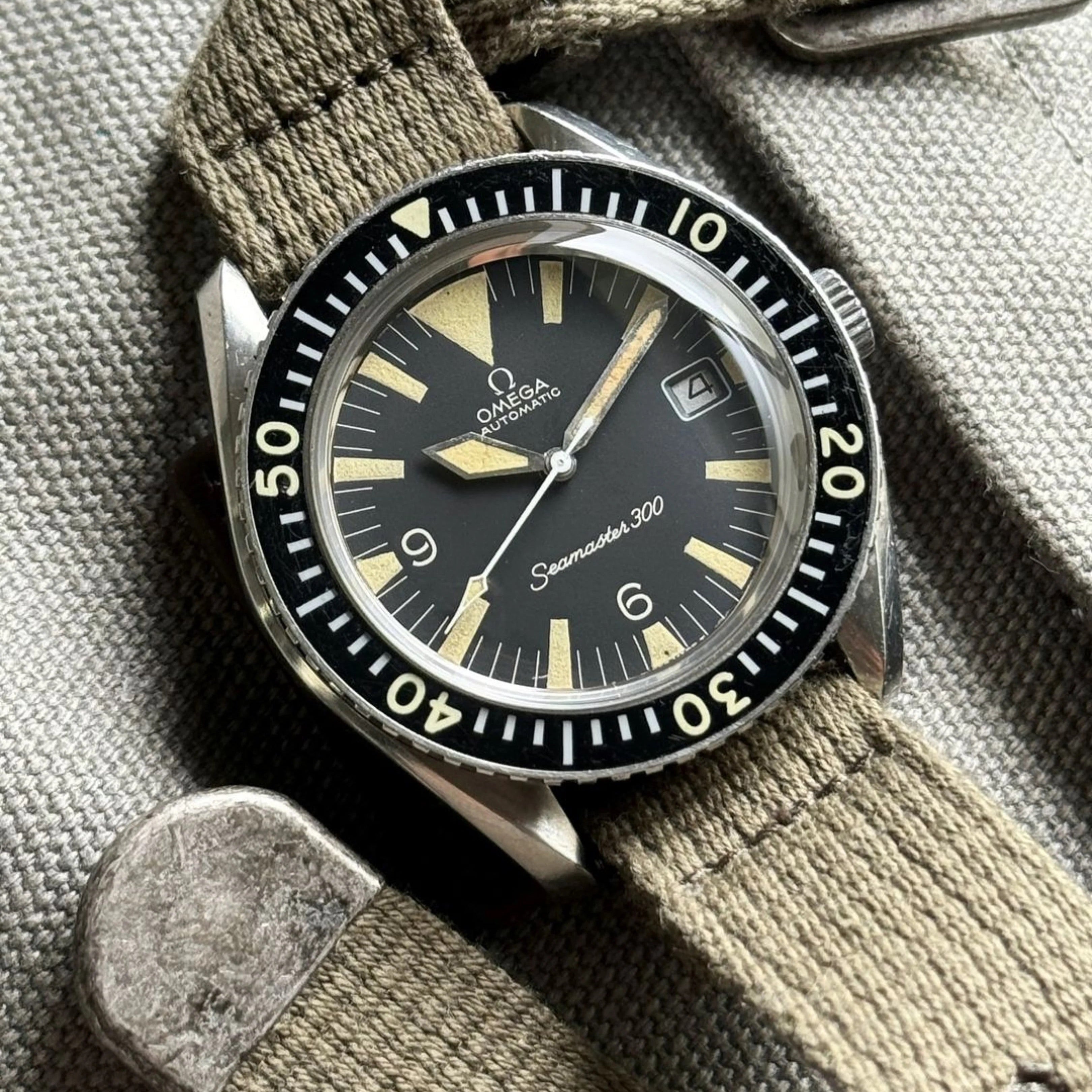 Omega Seamaster 300 (1960s) with big triangle and date, fitted on RSM's vintage military woven strap with distressed hardware.