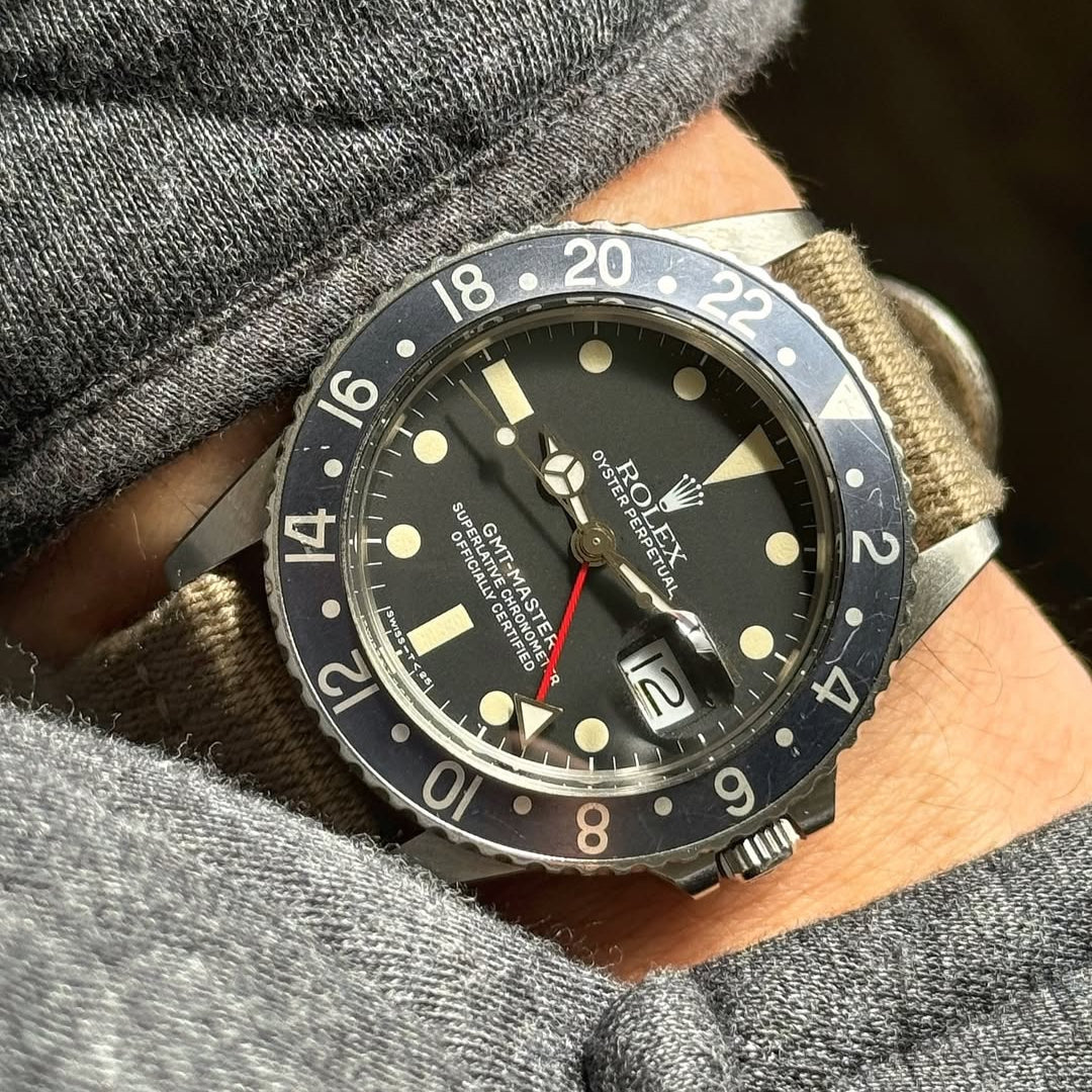 Vintage Rolex GMT with black bezel and red GMT hand worn on RSM khaki polycotton strap. Patina markers complement the vintage look.