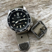 The Seiko vintage dive watch, with a worn black bezel and patina indices, is fitted with RSM's Khaki vintage military strap and distressed hardware.