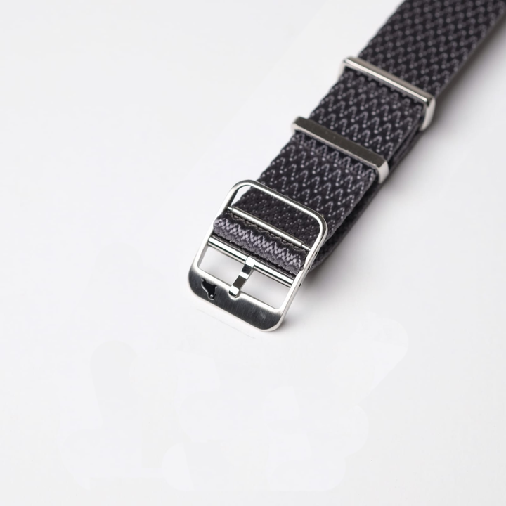 Close-up of the RSM Watch Straps Herringbone Twill in Field Gray, showcasing its zigzag fabric pattern, silver buckle, and loops.