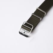 Close-up of an olive drab RSM Watch Strap, resembling a NATO band, crafted from woven nylon with a silver buckle and two metal loops for adjustment.