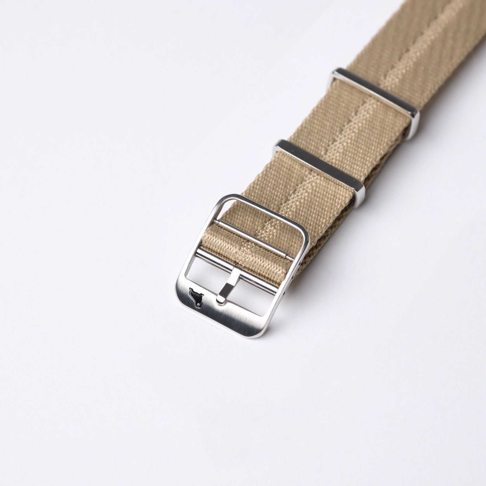 The RSM Engraved Stripe Stealth Khaki strap with a silver buckle and small dog logo is elegantly displayed on a light gray background.