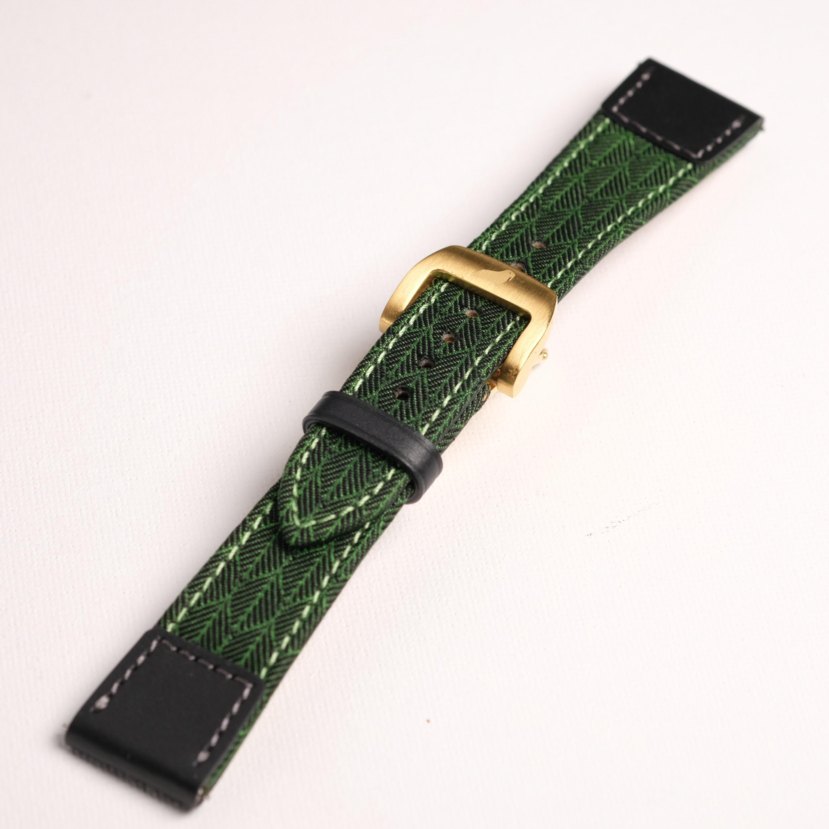The RSM Watch Strap Art Deco Silk Watch Strap in Green features a gold buckle, textured leaf pattern, black leather ends, and is Apple Watch-compatible, shown on a white background.