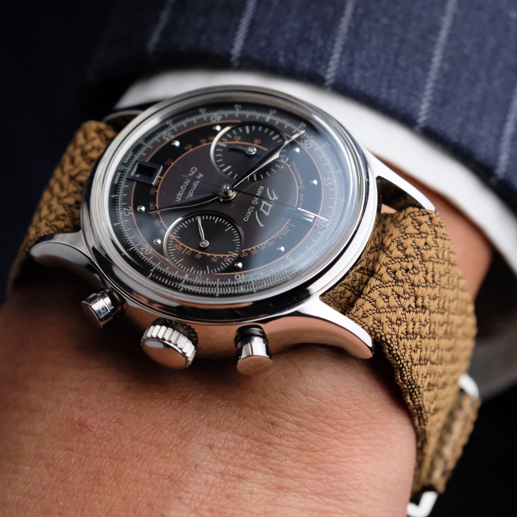 Man in a suit wearing a watch paired with the RSM Watch Strap Bronze Champagne 2-Piece Silk, showcasing elegance and luxury.