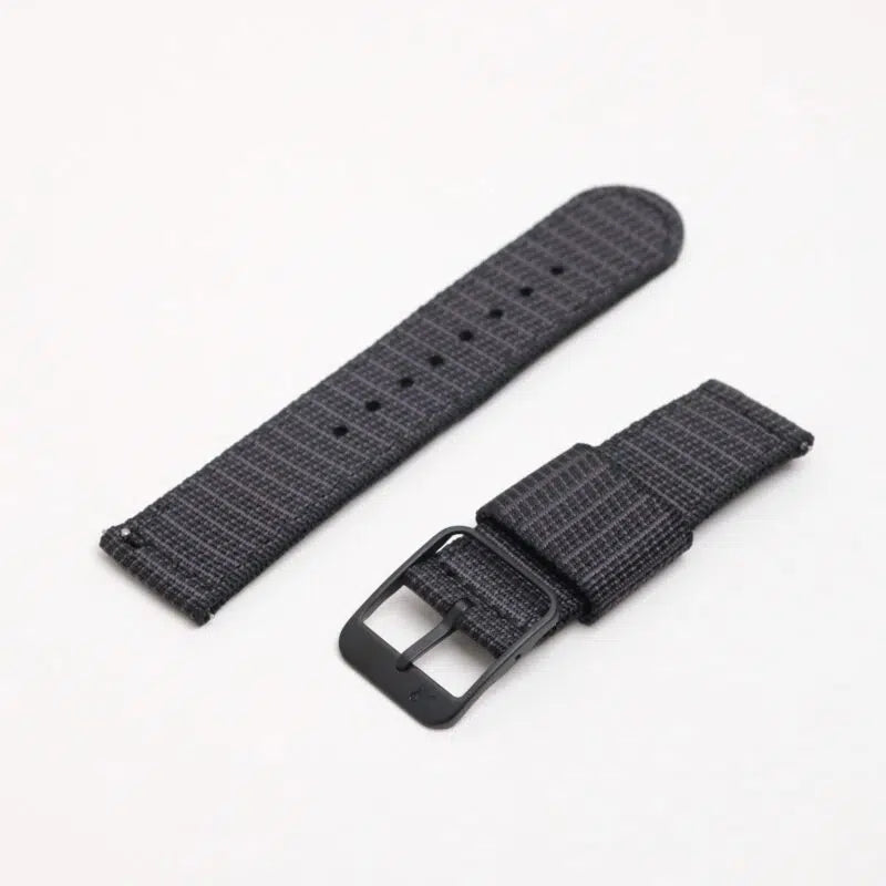 The RSM Watch Strap X-Hatch Single Pass in Black, made from durable black and gray textured polyester, is displayed in two pieces—one with a metal buckle—against a plain white background.