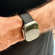 A close-up of a wrist wearing the RSM Watch Strap X-Hatch 2-Piece Watch Strap in Black with a silver-case apple watch, set against a black shirt background.