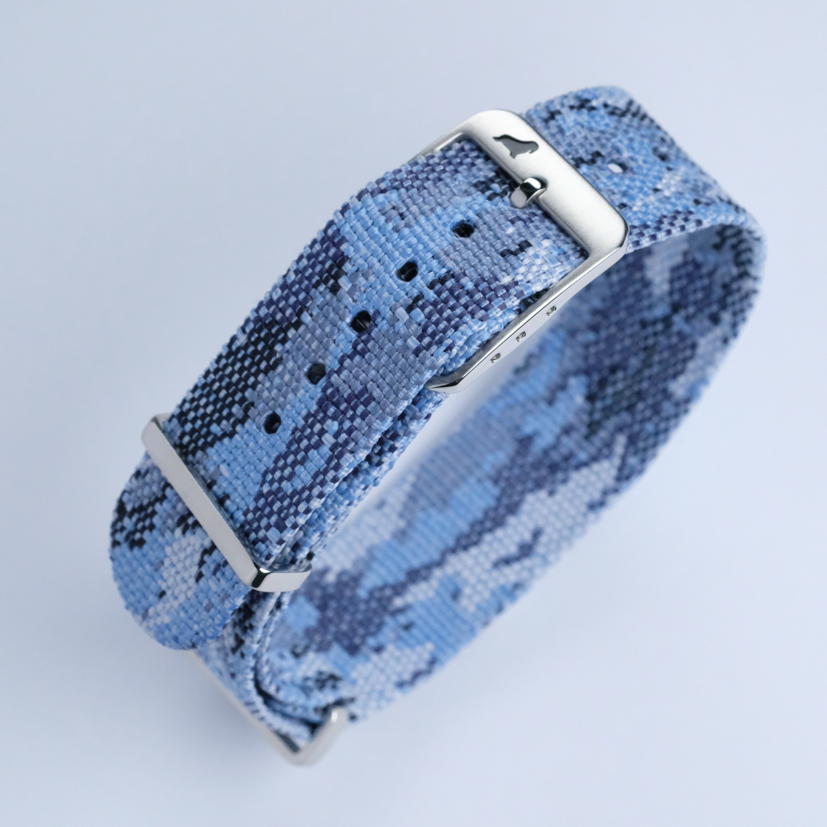 The RSM Watch Strap Ocean Camo Adjustable Single Pass Watch Strap, in blue and gray camouflage jacquard-woven polyester with 316L stainless steel hardware, is shown coiled on a white background.