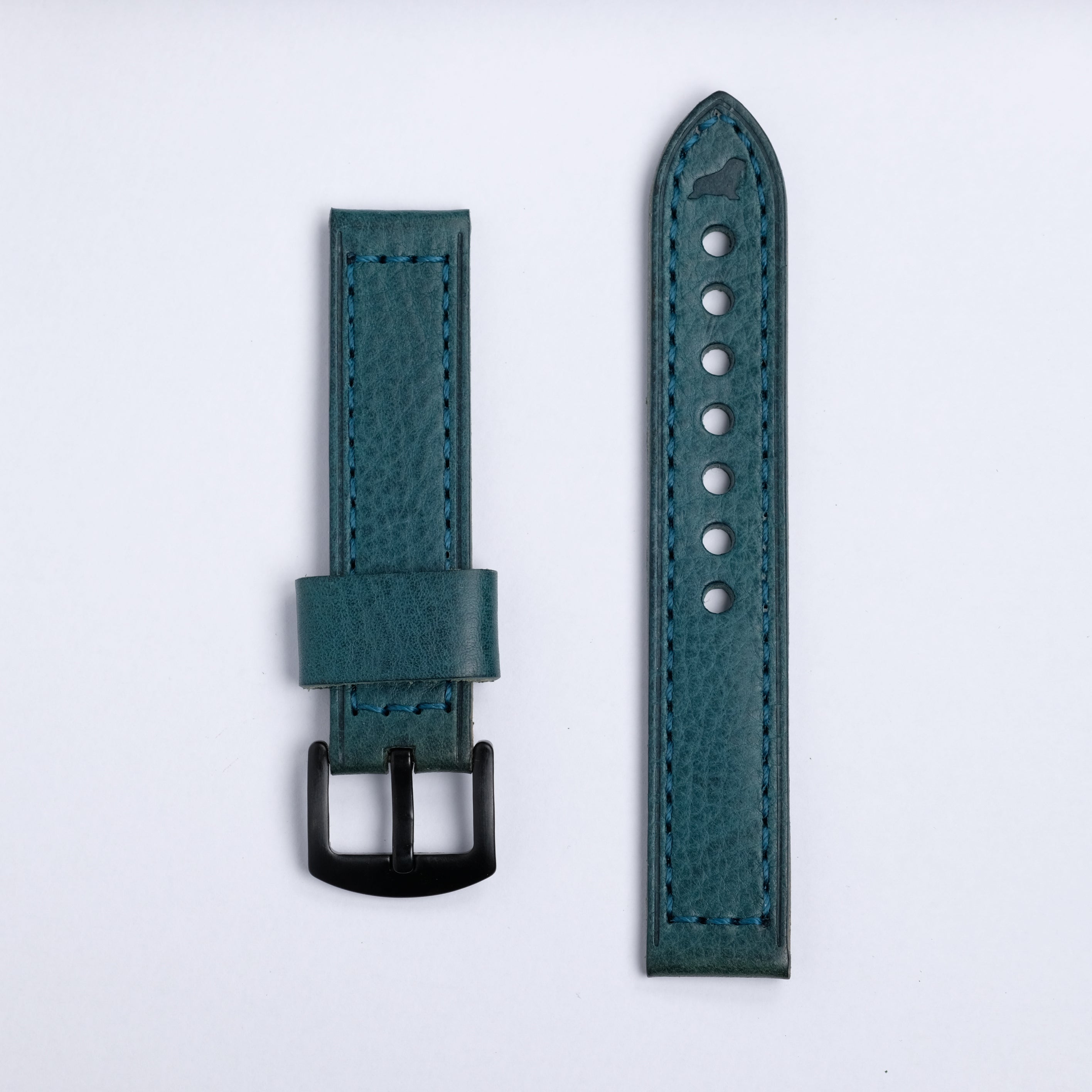 The Leather Watch Strap in Blue by RSM Watch Strap features teal leather in two pieces on a white background: the longer piece has multiple holes and a pointed tip, while the shorter one includes a black buckle and loop.