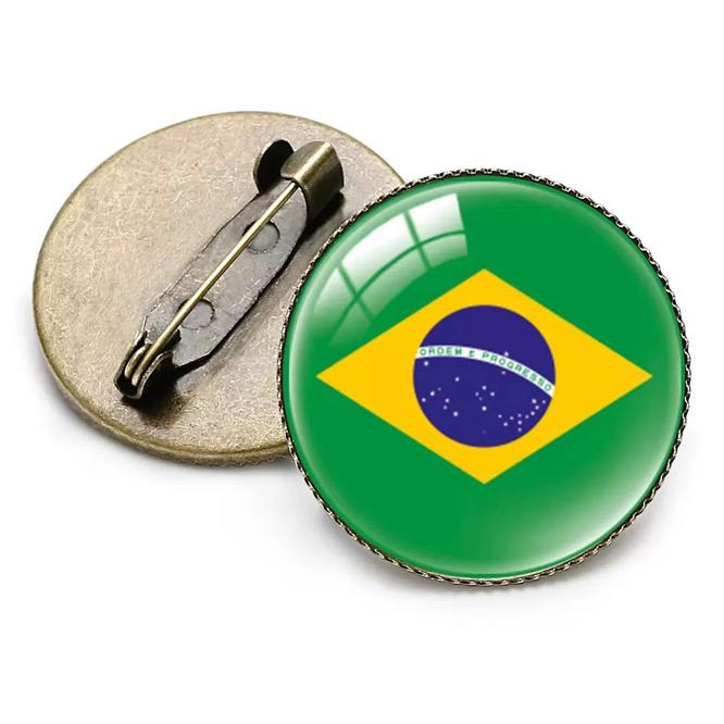 The RSM Watch Strap World Cup 2026 Pin is a round badge with Brazil's flag design and a metal pin clasp, shown front and back.