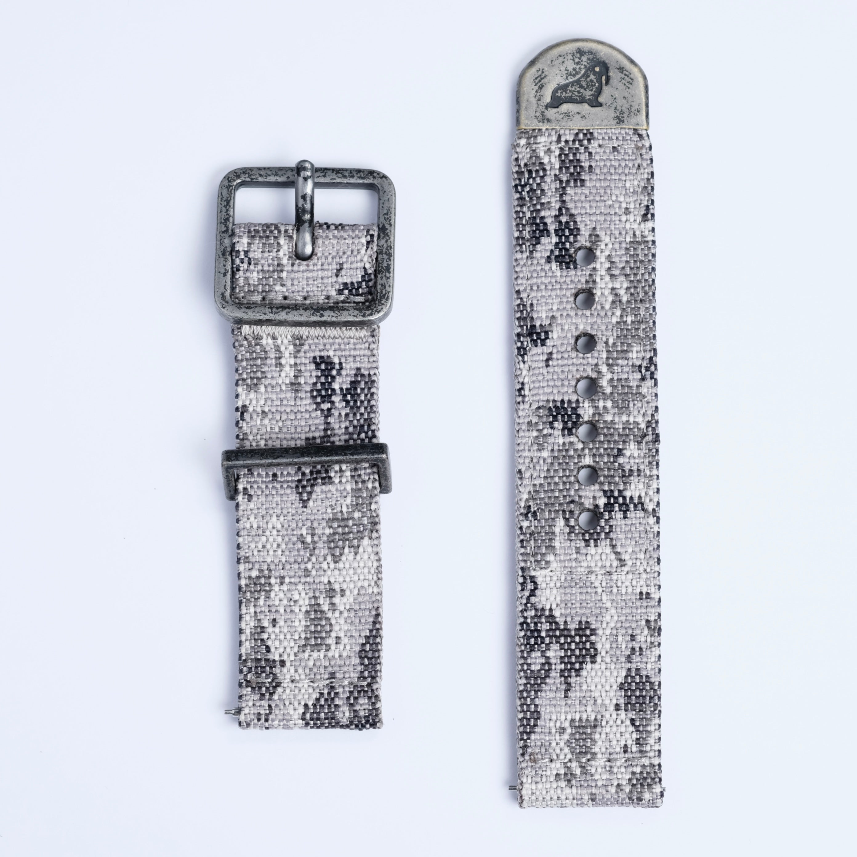 The RSM Watch Strap Snow Camo 2-Piece features a jacquard-woven gray and black camouflage design with metal buckle and tip engraved with an animal, shown on a white background.