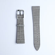 Two pieces of the RSM Watch Strap's Alligator Grain Calf Leather Watch Strap in Grey are shown: the left has a metal buckle and loop, the right is longer with holes. Both display fine Japanese craftsmanship on a white background.