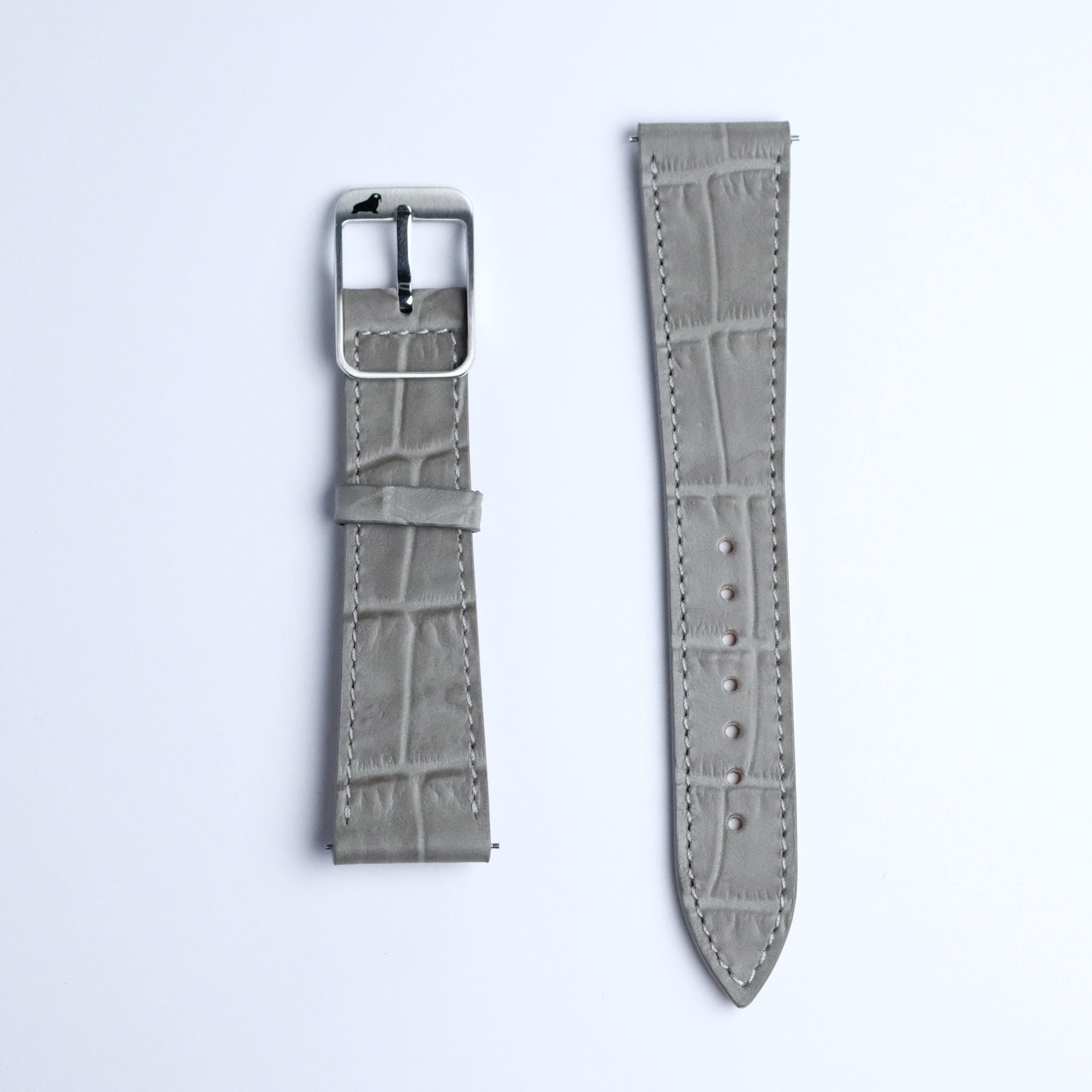 Two pieces of the RSM Watch Strap's Alligator Grain Calf Leather Watch Strap in Grey are shown: the left has a metal buckle and loop, the right is longer with holes. Both display fine Japanese craftsmanship on a white background.