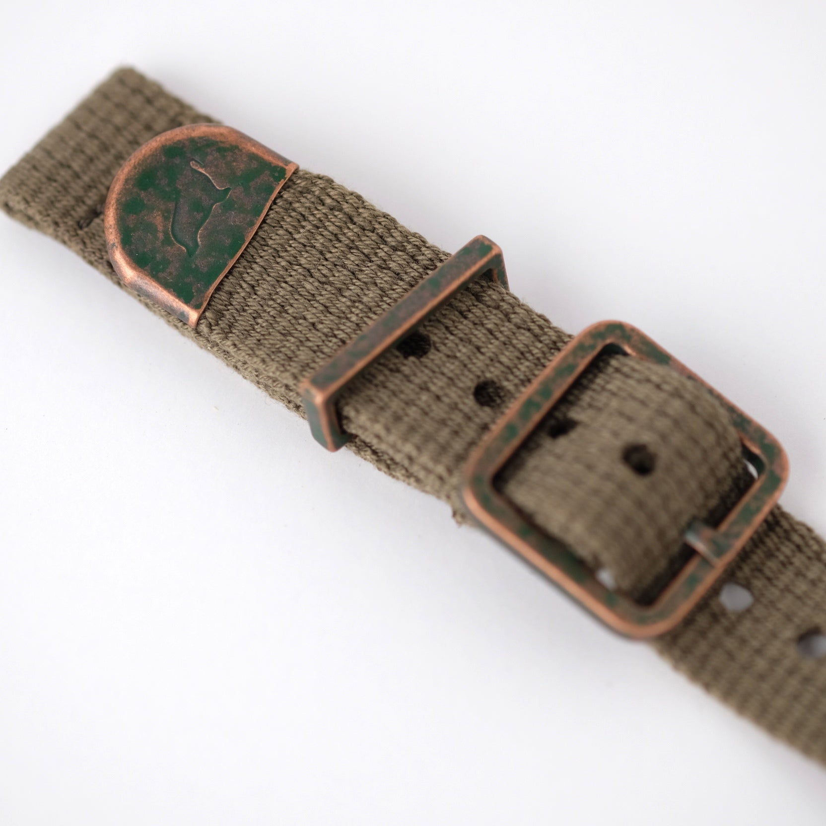 The green poly-cotton woven, vintage-style RSM watch strap features distressed bronze end caps, keeper, and a buckle with a green patina.