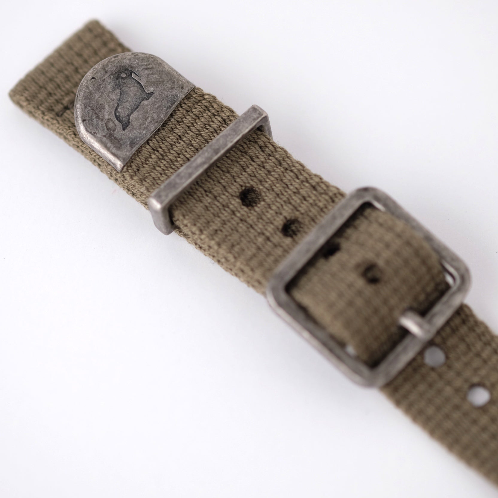 The green poly-cotton vintage-style watch strap features a distressed end cap with RSM's Walrus logo, along with a keeper and buckle.
