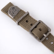 The green poly-cotton vintage-style watch strap features a distressed end cap with RSM's Walrus logo, along with a keeper and buckle.