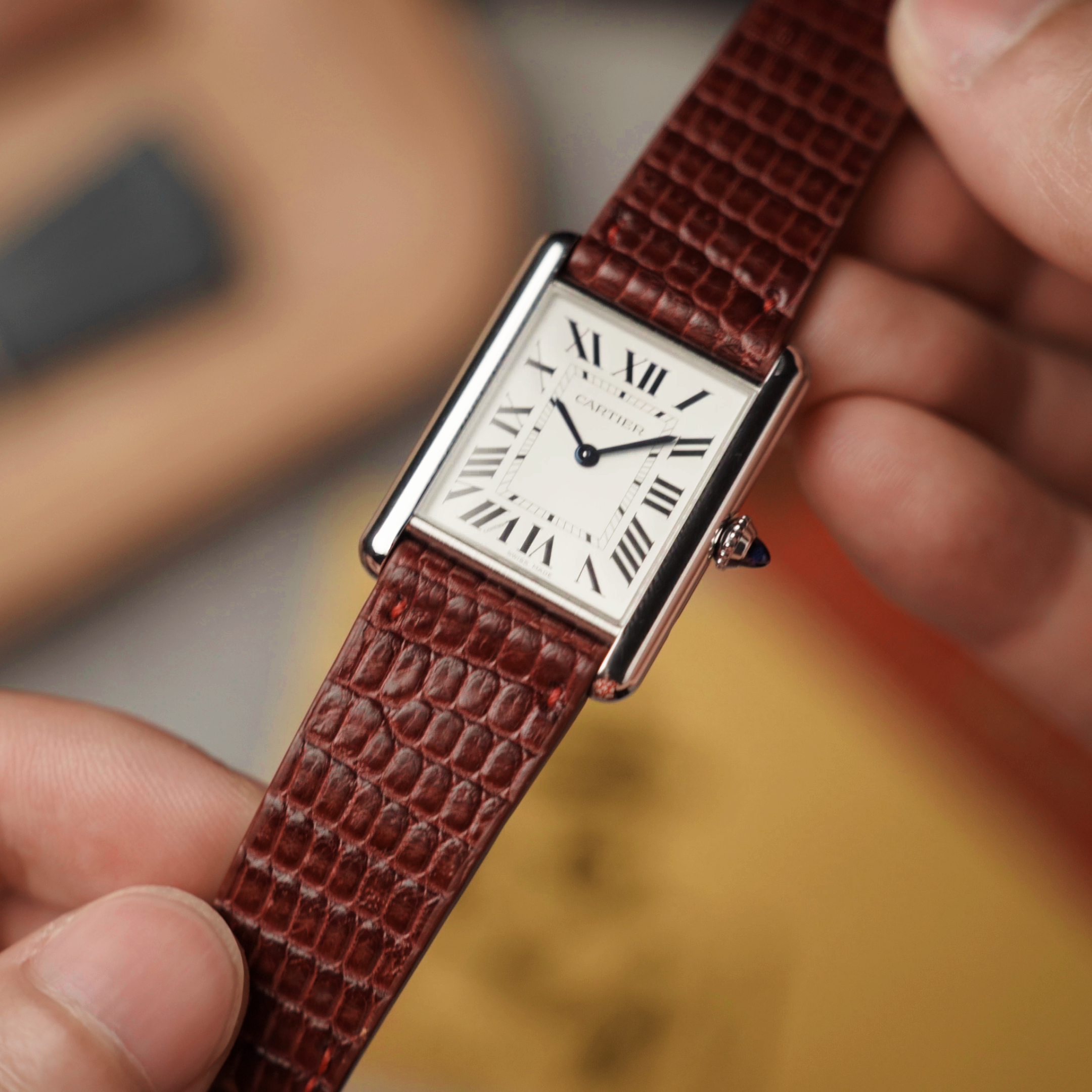 Person holding a Cartier watch with a red lizard leather watch strap by RSM