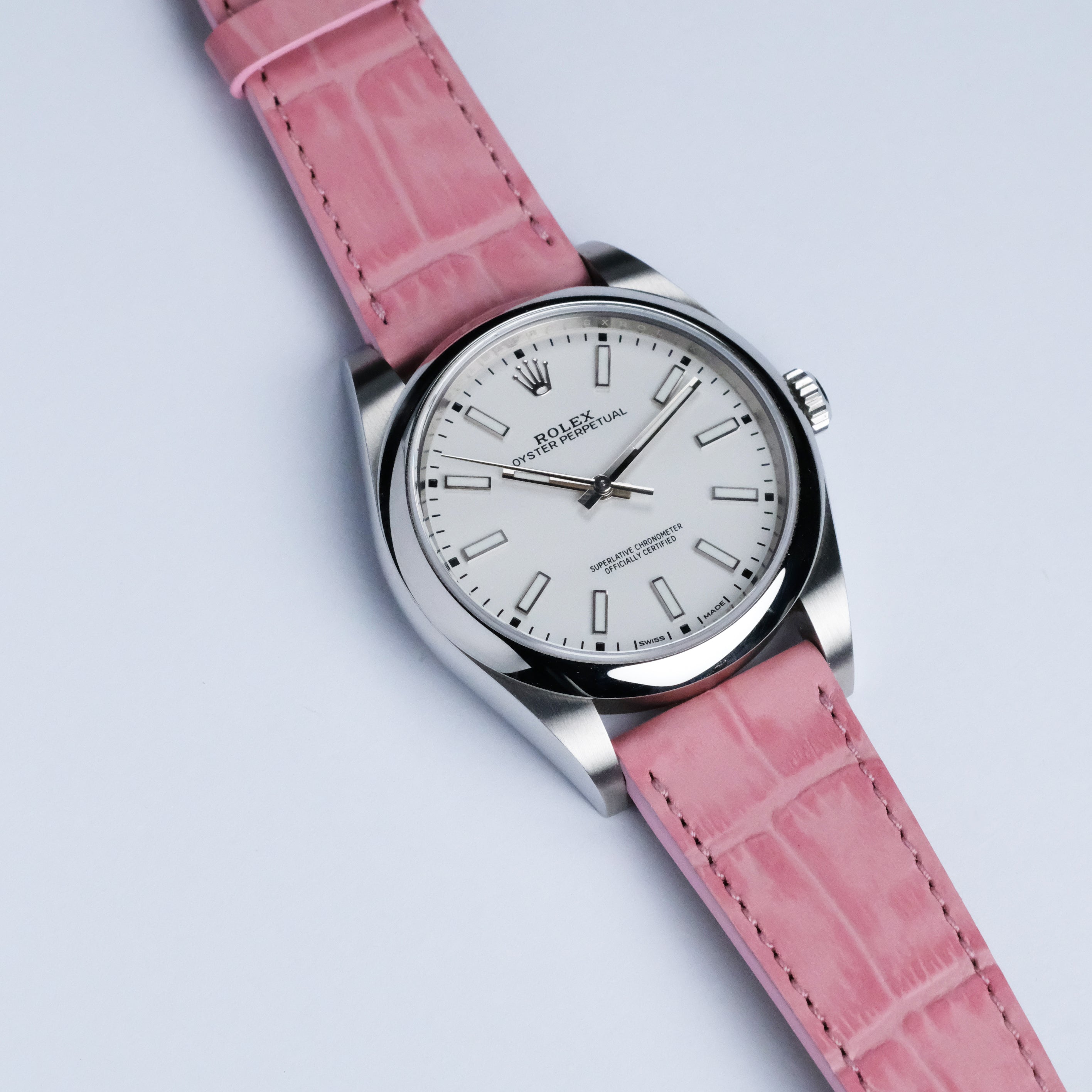 A white-dial Rolex Oyster Perpetual with an RSM Watch Strap Alligator Grain Calf Leather strap in pink, shown on a white background.