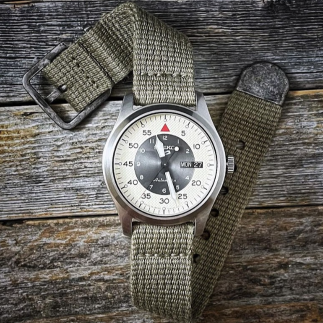 Seiko 5 mechanical field watch on RSM vintage cotton military strap, featuring a distressed silver buckle and end tip for a rugged look.