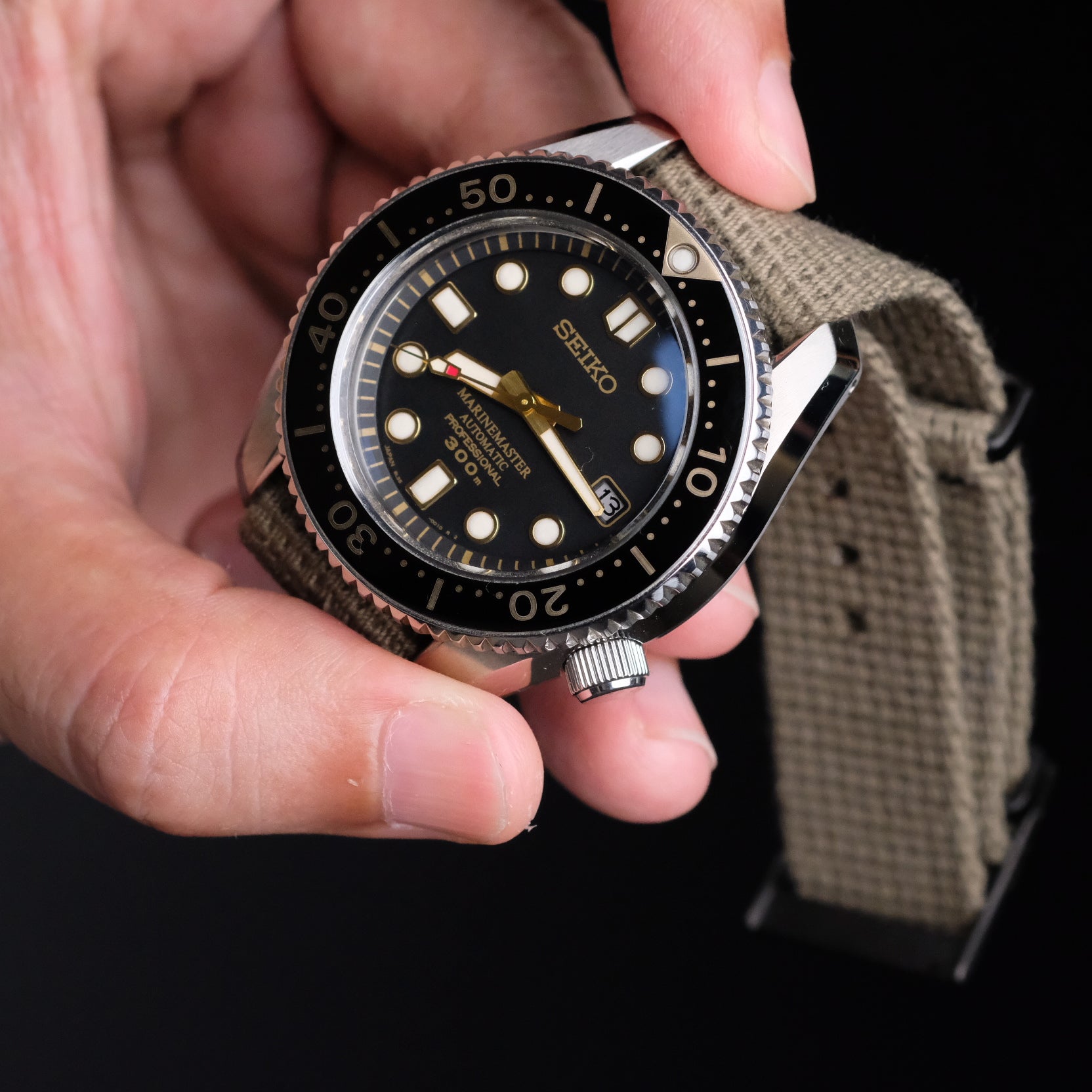 Hand holding a Seiko SBDX paired with a Vintage Military watch strap by RSM, showcasing its rugged design and distressed hardware.
