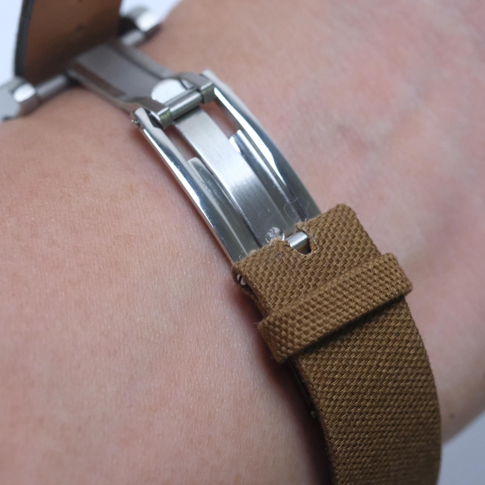 RSM fine canvas strap fitted on the deployant clasp, worn on the wrist with one side of the clasp in the open position.
