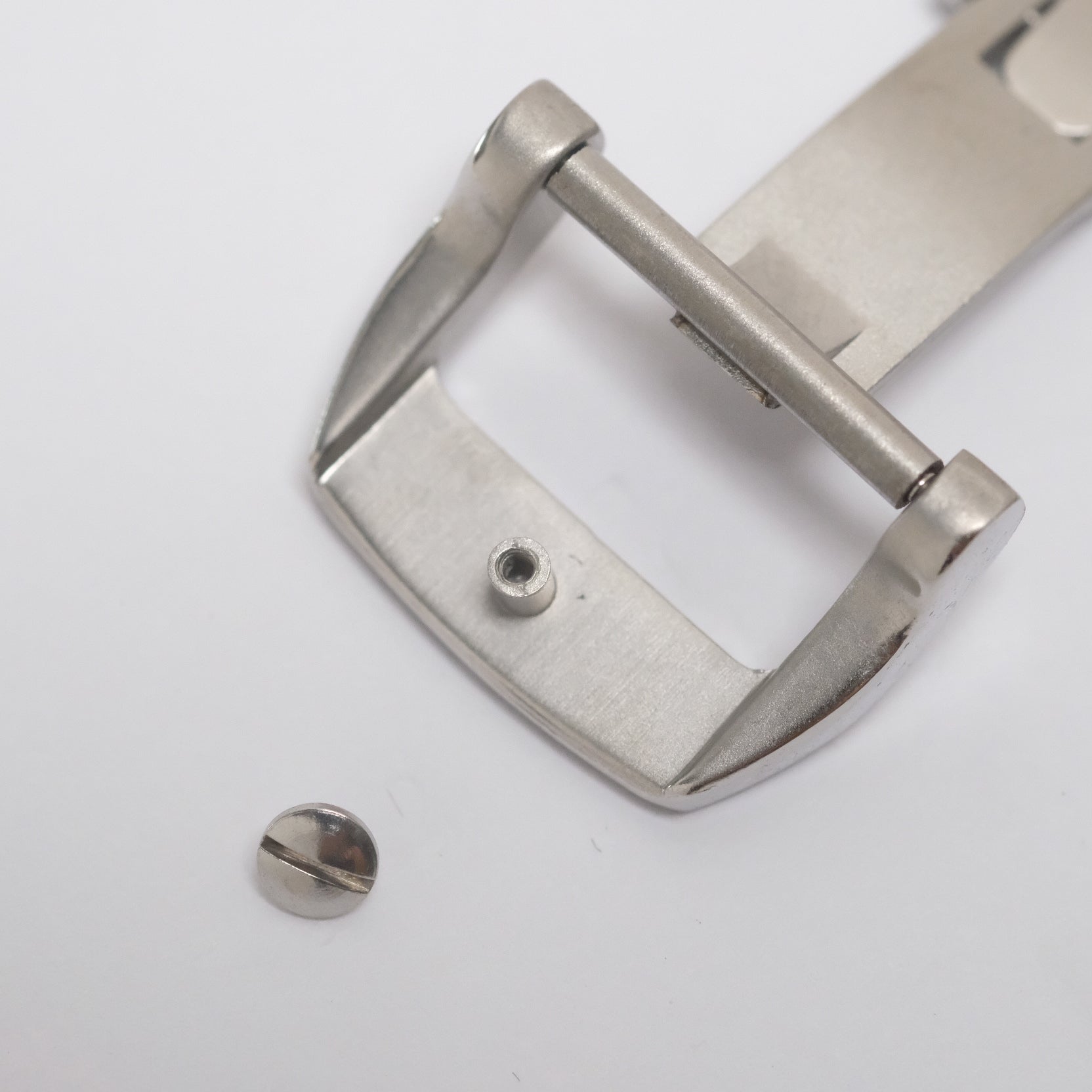 Steel spring-loaded deployant clasp with screw cap in open position, where it slots through the selected watch strap hole and secures it.