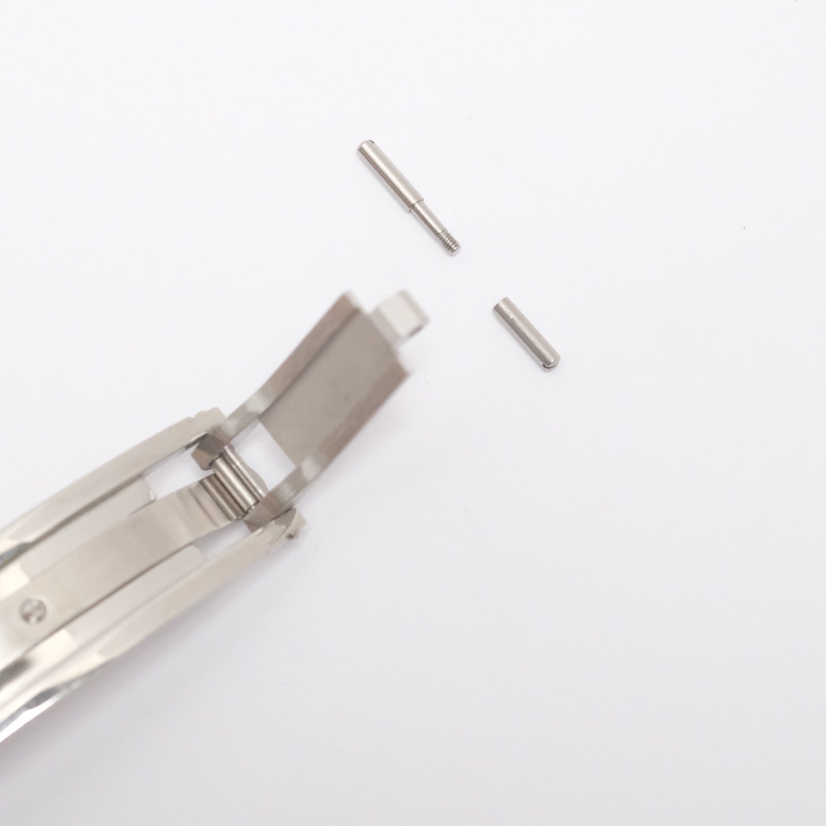 The end of the spring-loaded steel deployant clasp, where the tang buckle end is held by a pin and attached to the strap via a screw.