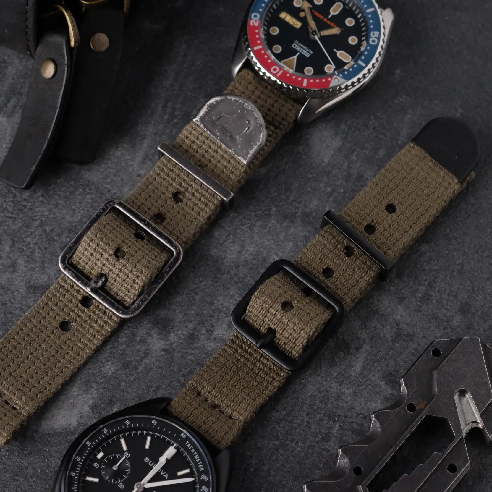 The green cotton woven strap is paired with a modded Seiko SKX Pepsi, featuring patina indices, and a Bulova chronograph with matte hardware.