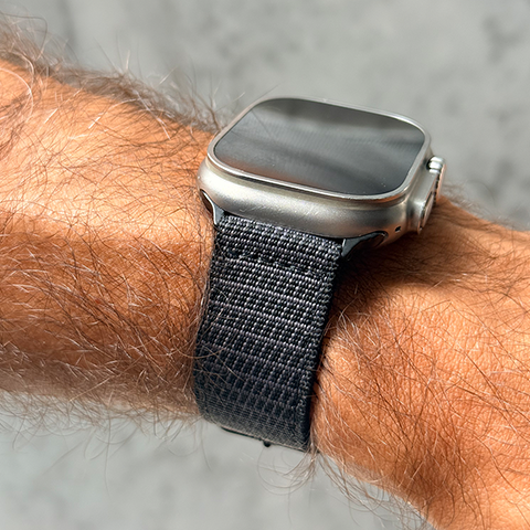 Apple watch with a black X-Hatch strap on a person's wrist against a neutral background