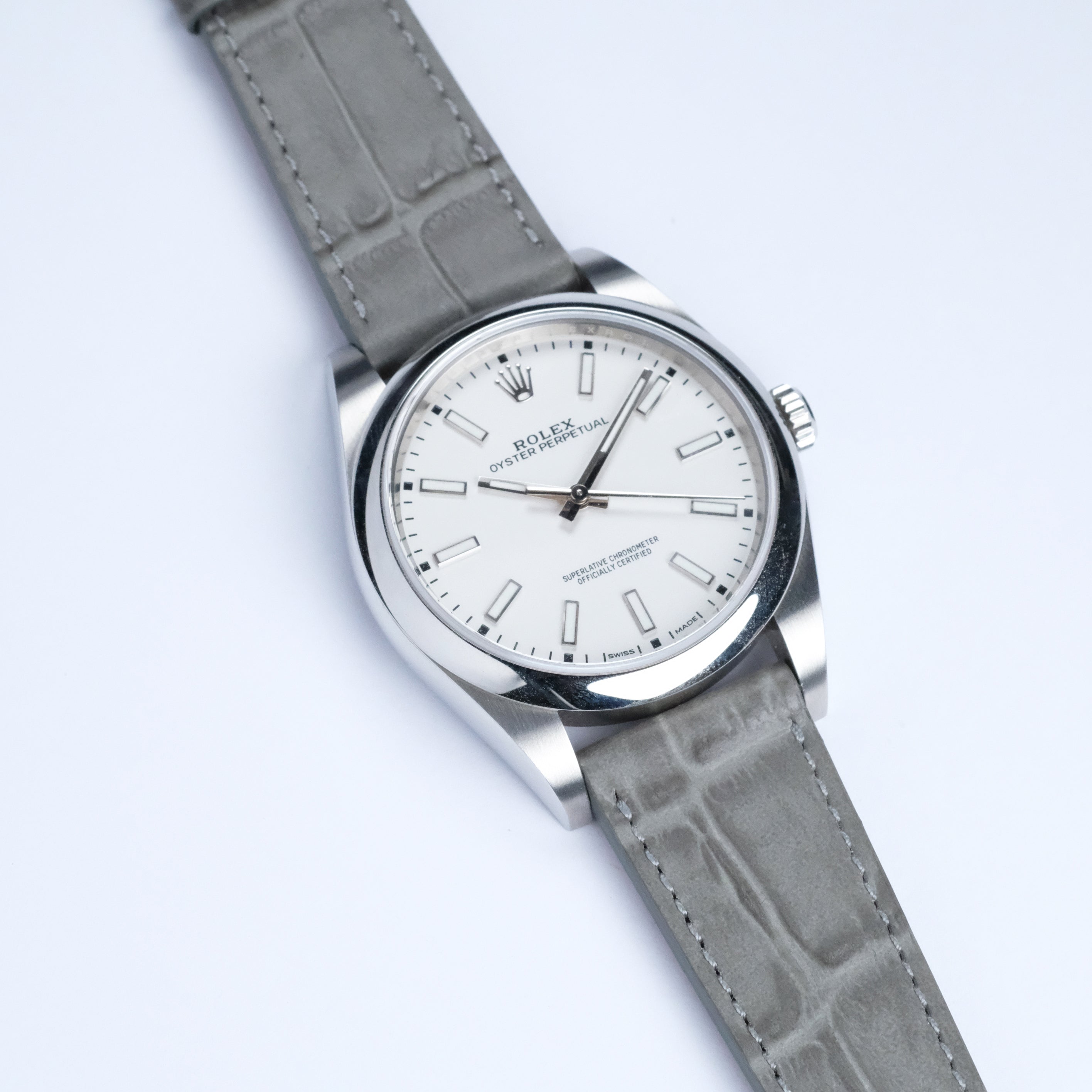 A RSM Watch Strap Alligator Grain Calf Leather Watch Strap in Grey is shown paired with a silver watch featuring a white dial and silver hour markers, photographed on a white background.