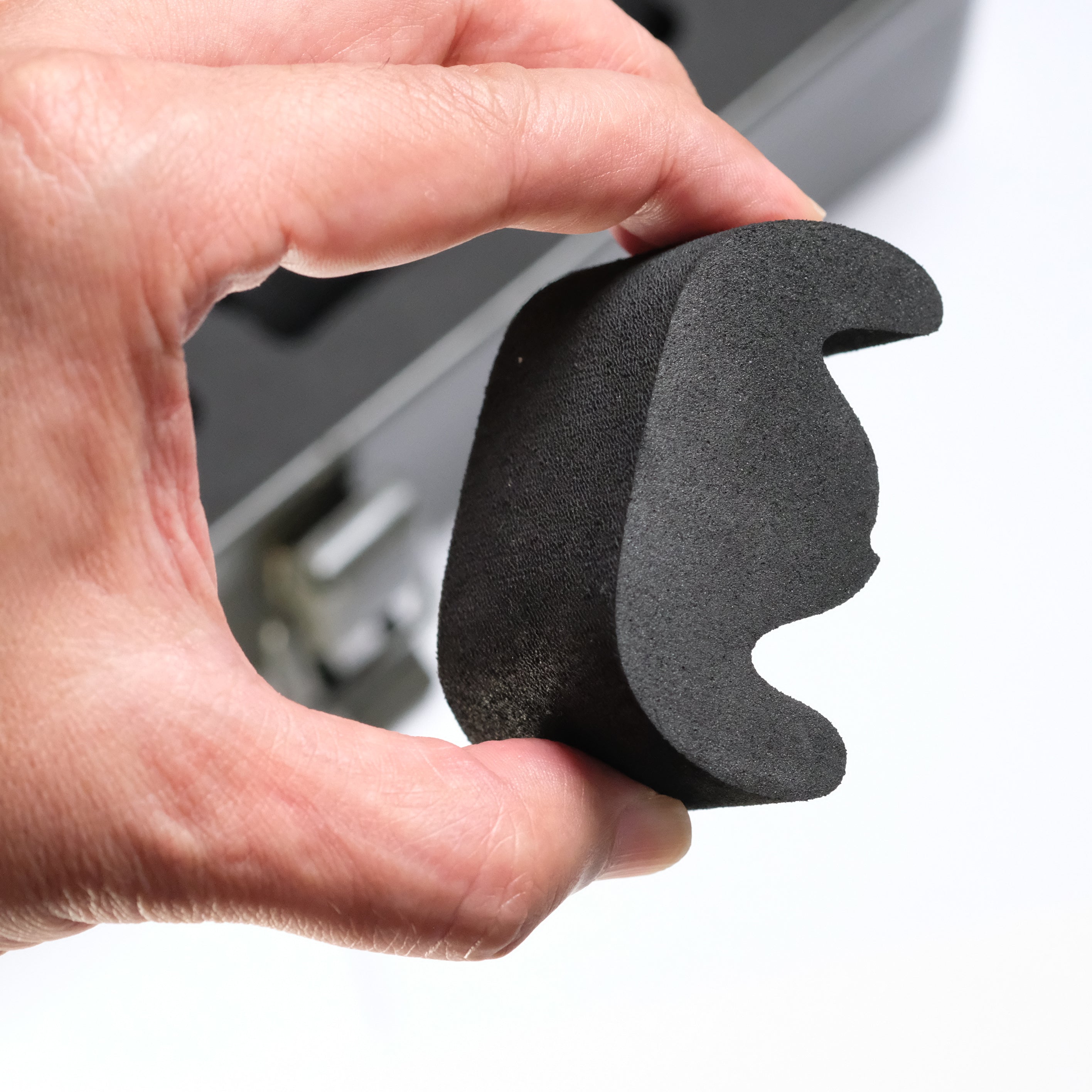 A hand holds a black foam piece shaped like the Batman logo, with a blurred background showing the RSM Watch Strap Watch Tool Box T-320—an ideal choice for EDC watch storage.