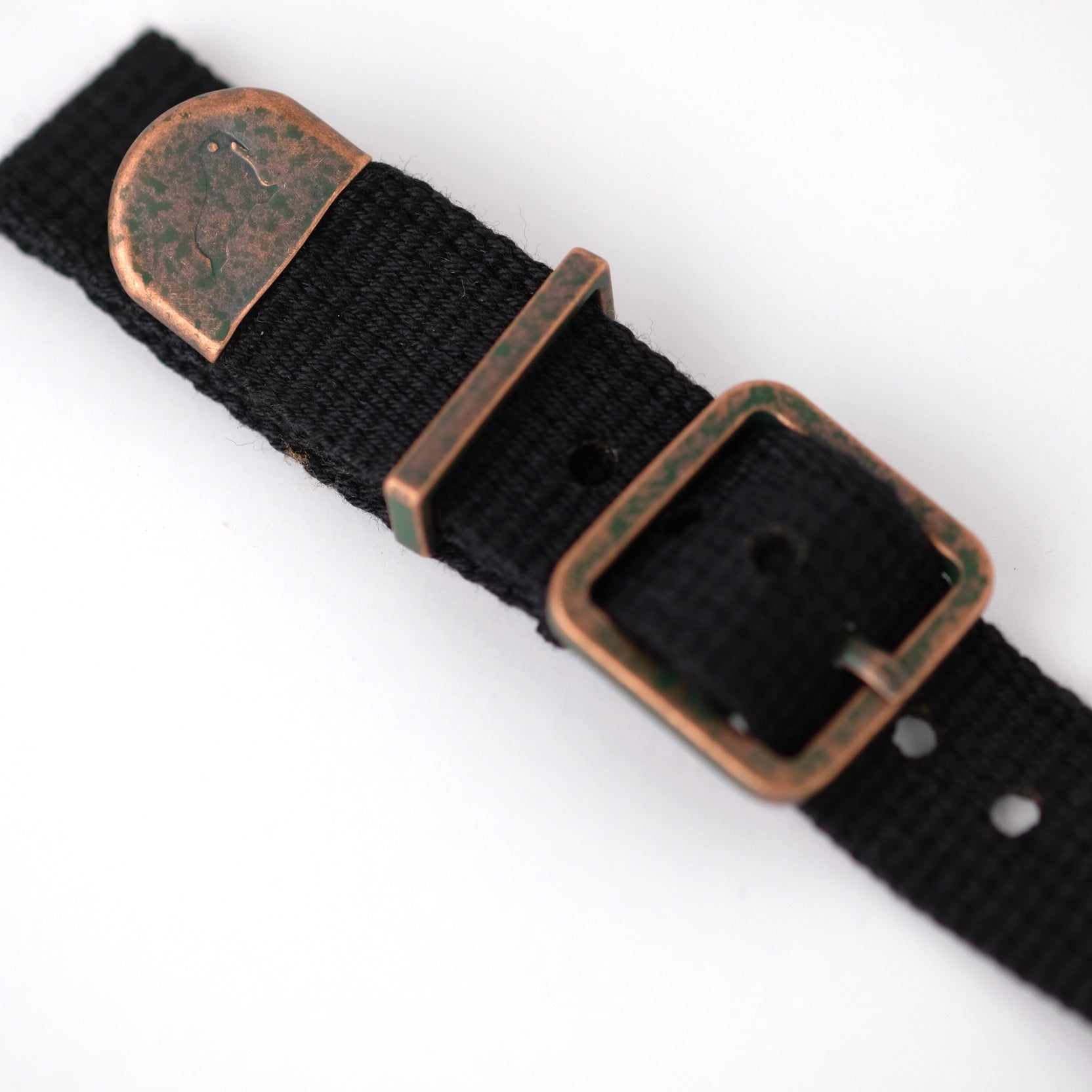 Close-up of RSM Vintage Military 2-Piece (Black) strap with distressed bronze hardware, multiple holes, and black polycotton fabric.