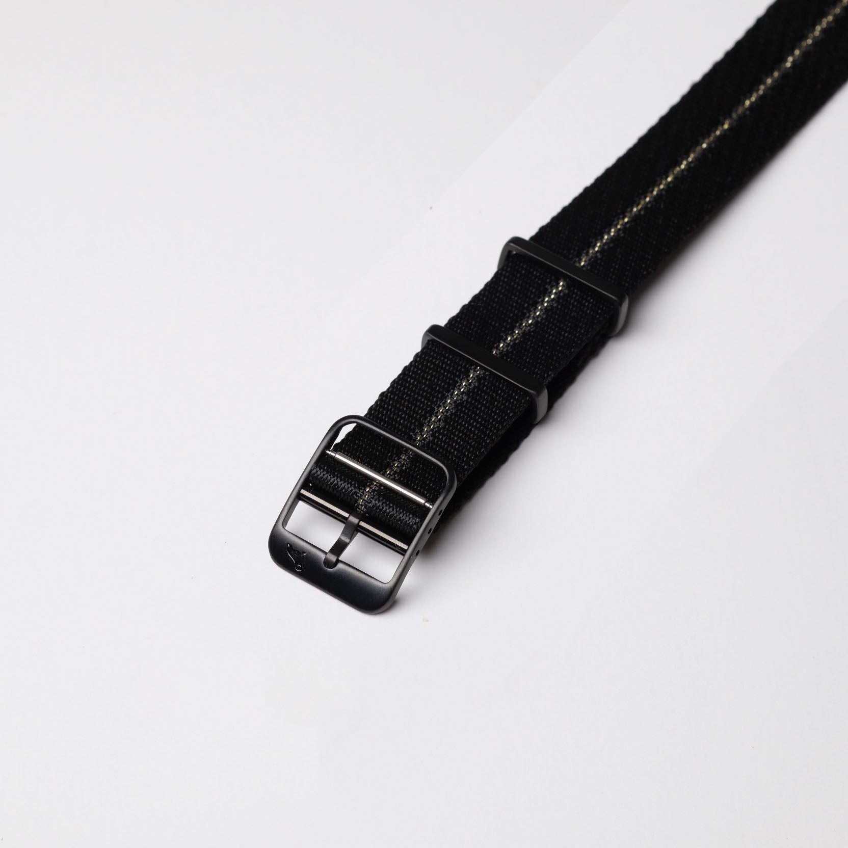 Close-up of the RSM Engraved Stripe in Gilt Stripe, black Jacquard weave with a light stripe and angled black buckle, displayed on white.