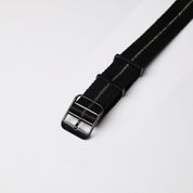 Close-up of the RSM Engraved Stripe in Gilt Stripe, black Jacquard weave with a light stripe and angled black buckle, displayed on white.
