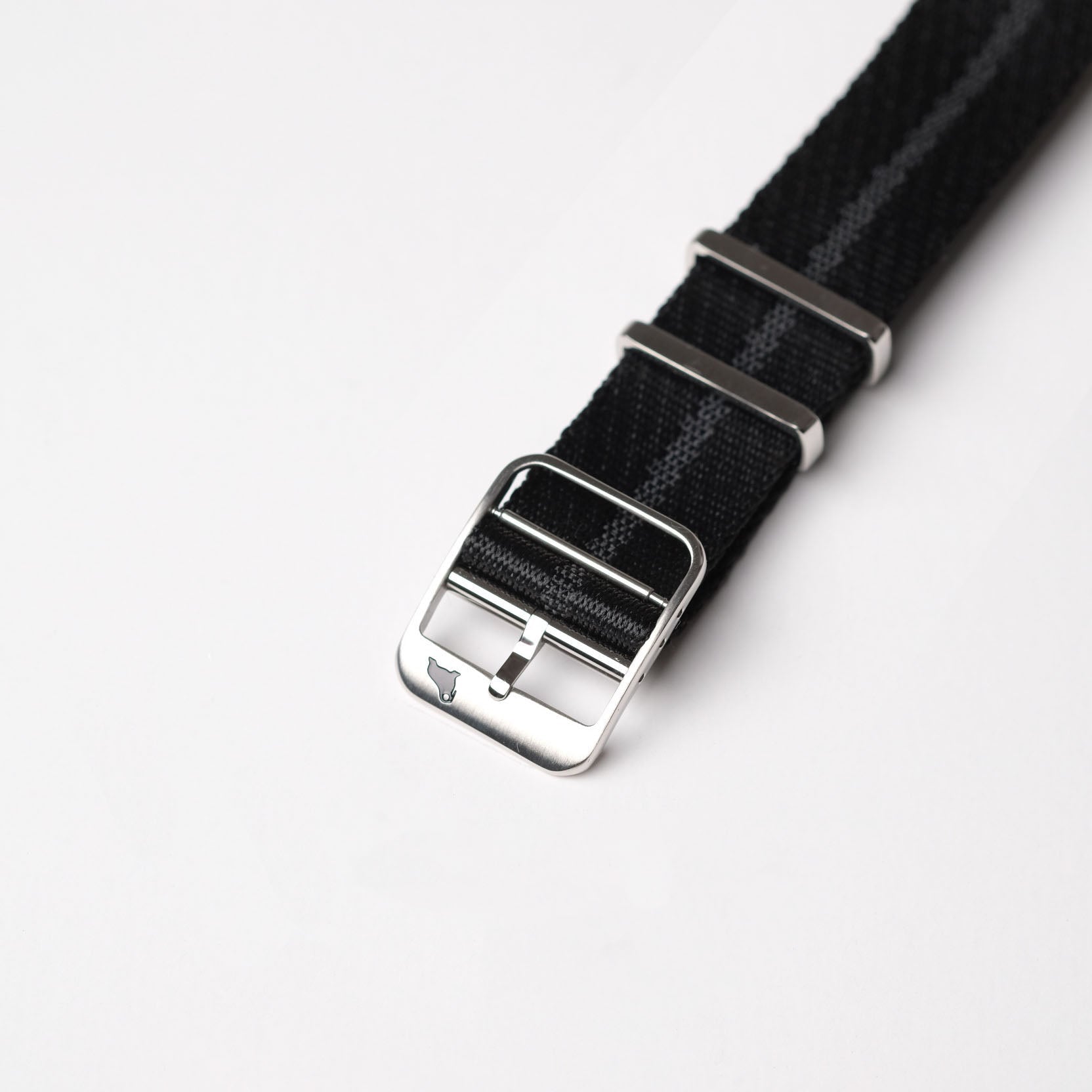 The RSM Watch Straps Engraved Stripe in Stealth Black features a jacquard weave, stainless steel buckle, and two securing metal loops.